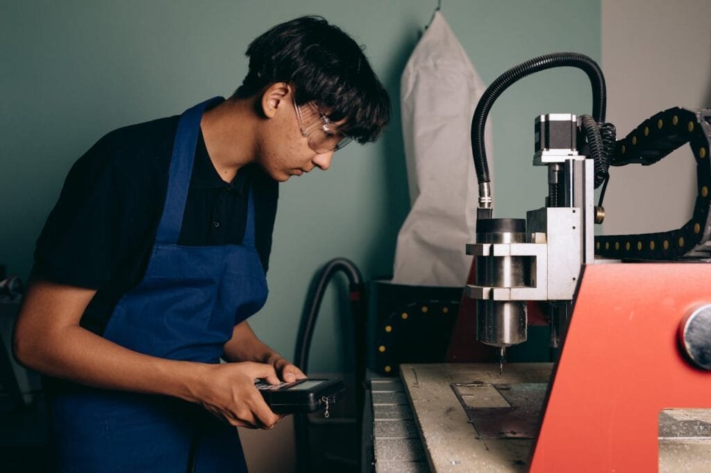 pexels-photo-9242167 Technician working with CNC machine in an industrial workshop setting, demonstrating concentration and expertise.